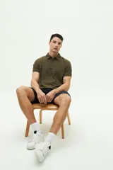 Remera polo verde militar con textura, corte regular, cuello clásico con detalles en azul marino y logo estampado en el pecho.