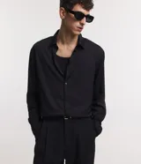 Camisa negra de poliéster con cuello inglés, manga larga, abotonada adelante y textura con rayas verticales.