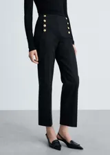 Pantalón negro de tiro medio con diseño crop, dos bolsillos laterales y cierre oculto de botón, gancho y cremallera.