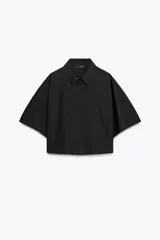 Camisa negra de popelín con cuello solapa y manga ancha por debajo del codo. Detalle de pinzas en la espalda y cierre frontal con botones ocultos por solapa.