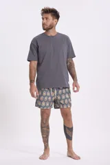 Short de baño con estampado de flores de loto y hojas en tonos amarillo, naranja y verde sobre fondo azul.