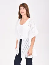 Blusa blanca con calados y mangas cortas amplias, con lazo de ajuste en la cintura.