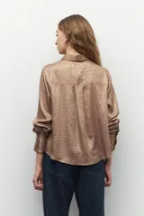 Camisa de manga larga de tela brillante y texturizada, con botones a tono y diseño versátil.