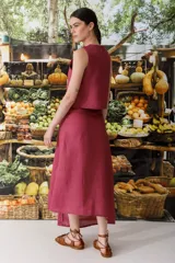 Conjunto de top sin mangas y falda midi color fucsia, con botones dorados. La falda presenta una abertura lateral.