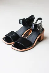 Sandalia de cuero negro con tira en el tobillo y tacón de madera, cómoda y ligera.