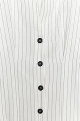 Camisa blanca con rayas verticales finas en color gris, de corte entallado, con cuello solapa y escote en pico. Cierre frontal con botones negros.