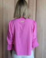 Blusa color lila claro, con cuello mao con volado y escote en V. Mangas largas con volumen y puños ajustados con elástico.