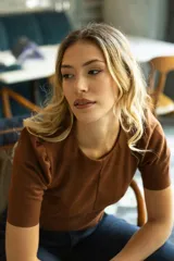 Top corto color verde militar, marca Tahari, confeccionado en símil gamuza. Tiene mangas cortas abullonadas, cuello redondo y cierre invisible en la espalda.