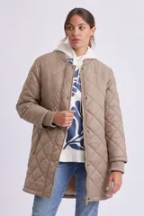 Campera larga acolchada color visón, con cuello redondo, cierre frontal con botones a presión y bolsillos laterales con cierre.