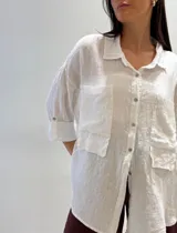 Camisa oversize rosada de lino, con cuello clásico, cierre frontal con botones, dos bolsillos de parche en el pecho y mangas largas con puños abotonados.