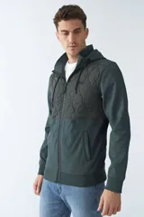 Campera verde oscuro de neopreno con capucha ajustable, cuello alto, bolsillos con cierre y logo en goma.