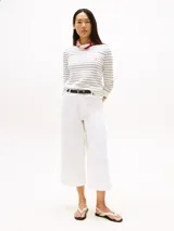 Sweater de punto de algodón orgánico a rayas horizontales blancas y negras, con cuello barco y puños con ribete rojo y azul. Logo de Tommy Hilfiger bordado en el pecho.