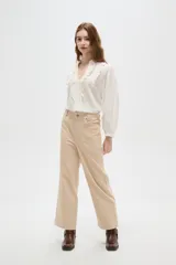 Pantalón de algodón color beige, de tiro alto, corte ancho y largo, con bolsillos frontales tipo parche.