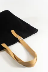 Cartera maxi negra de tela con asas de cuero color beige y bolsillos laterales.