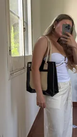 Bolso tote negro con textura símil cuero de cocodrilo, bolsillo externo color beige y asas marrones.