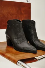 Botas negras de cuero vacuno con detalles de textura de piel de serpiente y tachas. Tienen punta fina y taco cuadrado.