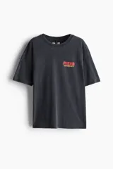 Remera negra de corte amplio con cuello redondo y mangas cortas. Estampado frontal con la palabra 'PACHA' en color rojo y tipografía retro.