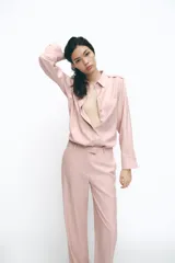 Camisa color rosa de manga larga, con cuello solapa, trabillas en los hombros, bolsillo delantero y cierre frontal con botones.