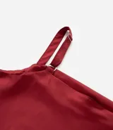 Musculosa color rojo oscuro, confeccionada en satén, con escote drapeado (degagê) y breteles ajustables. El bajo de la prenda es asimétrico.