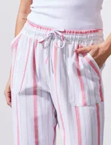 Pantalón de lino a rayas verticales color beige y blanco, con pretina ancha elastizada, lazo de ajuste y bolsillos inclinados.