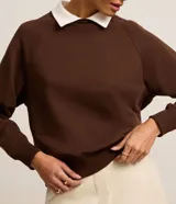 Sweater marrón de algodón con cuello camisero blanco, corte recto y mangas largas raglán.