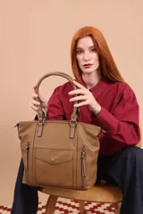 Cartera bandolera de símil cuero color marrón claro, con doble asa rígida y correa regulable. Presenta dos bolsillos frontales con cierre vertical y un bolsillo frontal con solapa y botón. Cuenta con dos divisiones internas.