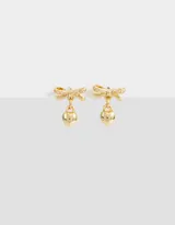 Par de aros pasantes dorados con forma de moño con incrustaciones de strass y dije colgante de corazón liso.