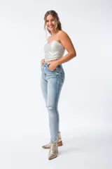 Pantalón de jean celeste con roturas en las rodillas, corte skinny, tiro alto y cierre frontal con botones.