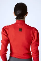 Polera roja de tejido de punto con cuello alto y mangas largas abullonadas en los hombros.