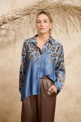 Camisa celeste con estampado animal print en tonos marrones, de seda, con cuello camisero, cierre frontal con botones y mangas 3/4.
