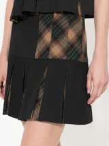 Minifalda negra de twill con tablas y tela estampada en la parte interna de las tablas.