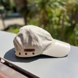 Gorra de cuero color dorado con etiqueta de cuero marrón con el logo de la marca "Bona".