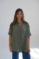 Camisa verde seco de lino, con cuello mao, mangas cortas con dobladillo y cierre frontal con botones.