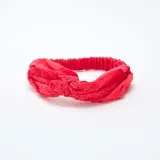 Diadema roja con detalle de bordado inglés y elástico en la parte posterior.