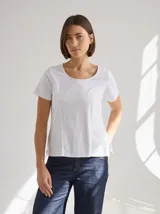 Remera blanca de algodón y spandex, de manga corta y cuello redondo. Presenta costuras verticales en el frente que estilizan la figura.