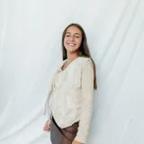 Chaleco corto color crema con escote en V, sisa redonda y cierre delantero con botones.