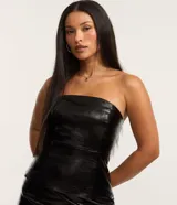 Blusa corta de cuero sintético negro, sin mangas, con cuello alto de encaje y cierre lateral con cremallera.