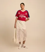 Pollera midi evasé de encaje color blanco, con cintura elástica, forro corto y bajo asimétrico.