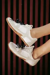 Zapatillas urbanas de cuero color tostado, con cordones verdes y suela de goma.