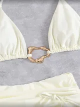Conjunto de bikini blanco compuesto por un corpiño triangular con detalle de aro dorado y una bombacha con tiras laterales ajustables.
