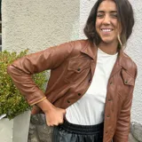 Campera marrón de cuero ovino con cuello clásico, cierre frontal con botones a presión, bolsillos con solapa en el pecho y mangas largas con puños abotonados.