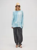 Buzo de algodón con efecto tie-dye en tonos celeste y blanco, de corte holgado y largo por debajo de la cintura, con puños acanalados.