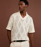 Camisa polo de mangas cortas color crema, confeccionada en tejido de punto calado con cuello inglés.