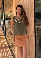 Top color beige de cuero con flecos en los laterales y caracoles buzios en el frente. Espalda tejida.