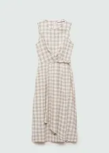 Vestido midi a cuadros color beige con líneas marrones, de corte evasé, sin mangas y con cuello redondo. Presenta un detalle cruzado en la cintura.