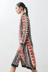 Vestido camisero midi con estampado abstracto en tonos beige, rojo y negro.