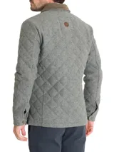 Chaqueta acolchada gris con patrón de rombos, cuello de pana marrón, cierre con broches metálicos, bolsillos frontales y bolsillo interno.