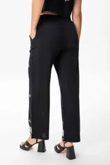 Conjunto de chaleco y pantalón de lino negro con bordado blanco. El chaleco es abierto con tiras ajustables y el pantalón es de corte sastrero con elástico en la parte trasera de la cintura.