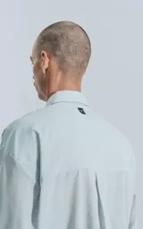 Camisa manga larga verde agua con bolsillo en el pecho, de calce oversize confeccionada en textil plano fresco y liviano.