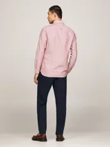 Camisa Tommy Hilfiger de corte slim fit, confeccionada en algodón Oxford con textura dobby. Diseño liso color salmón, con cuello abotonado, mangas largas con puños redondeados y logo bordado en el pecho.
